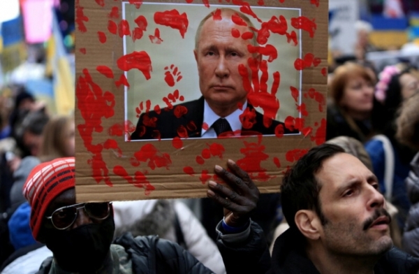 지난 5일(현지시각) 미국 뉴욕에서 러시아의 우크라이나 침공을 규탄하는 시위대가 블라디미르 푸틴 러시아 대통령의 얼굴 사진에 피 묻은 손바닥 자국을 찍은 손팻말을 들고 있다.ㅣ로이터